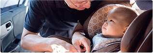 Parent buckling baby into a car seat